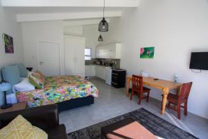 a bedroom with a bed and a table and a kitchen at Pine Park Garden Cottages in Johannesburg