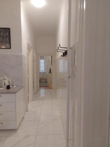 um corredor branco com paredes brancas e piso em azulejo branco em Melinda Apartman 2 em Budapeste