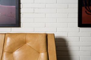 a brown leather chair in front of a white brick wall at Praktik Bakery in Barcelona
