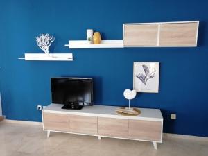 un soggiorno con una TV su una parete blu di La Buganvilla Beach House a Calahonda