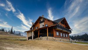 a wooden house sitting on top of a field at Cabana La Fermă in Vatra Dornei