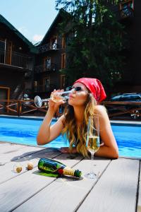 Eine Frau, die ein Glas Wein neben einem Pool trinkt. in der Unterkunft ZimaSnow Ski & Spa Club in Bukowel