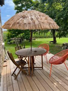 une table et des chaises sous un parasol de paille sur une terrasse dans l'établissement In the heart of artists's house, à Espiens