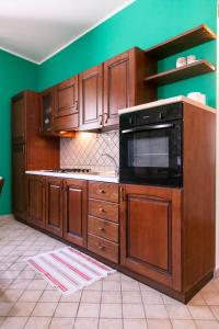 a kitchen with wooden cabinets and a green wall at Monolocale il Tindaro in Catania