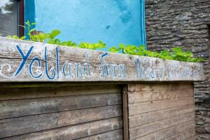 a wooden sign on the side of a building with plants at Sandy Cove Cottage in Combe Martin