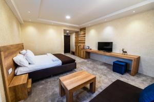 ein Hotelzimmer mit einem Bett und einem Flachbild-TV in der Unterkunft Magnolija Resort Ponikva in Kočani