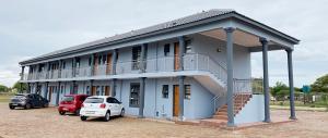 a building with cars parked in a parking lot at Nandi Gosa Apartments in Mahikeng