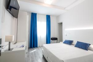 a bedroom with a bed and a tv and blue curtains at Acqua & Sale Hotel in Cervia