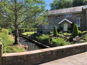 a stone house with a stream in front of it at Picket Post House Bed & Breakfast in Catterall