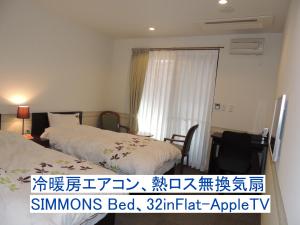 a hotel room with two beds and a window at B&B Hotel Hyochoan in Karuizawa