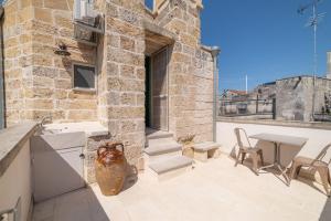 a stone building with a patio with a table and chairs at Lu Focalire Casa Vacanze in Carpignano Salentino