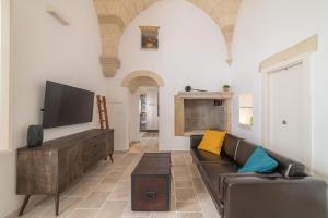 a living room with a couch and a tv at Lu Focalire Casa Vacanze in Carpignano Salentino