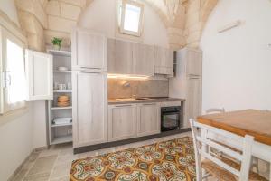eine Küche mit weißen Schränken und einem Tisch in der Unterkunft Lu Focalire Casa Vacanze in Carpignano Salentino