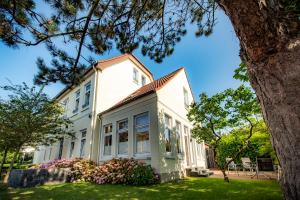 a white house with a tree at Familienhaus Feuerstein in Wangerooge