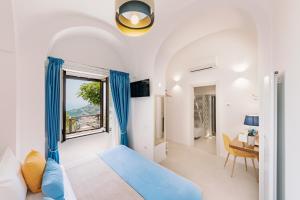 a bedroom with a blue bed and a window at Monte Brusara Relais in Ravello