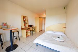 a bedroom with a bed and a table in it at Résidence Columba - Apparts meublés Agen Sud in Agen