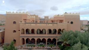 un grande edificio marrone chiaro con un balcone di fronte di Hotel Kasbah Lamrani a Tinerhir