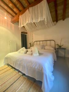 un dormitorio con una cama con sábanas y almohadas blancas en Casa antica toscana, en San Casciano in Val di Pesa