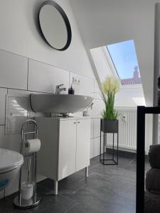 a white bathroom with a sink and a mirror at city roof in Teterow