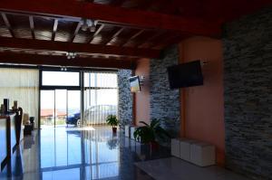 ein Wohnzimmer mit einem TV und einer Steinmauer in der Unterkunft Rahuen Hotel/Restaurant in Carpintería