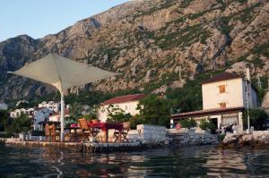 a table and chairs with an umbrella on the water at Casa Pantagana in Kotor