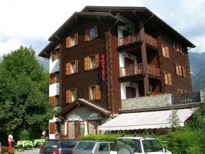 un grand bâtiment avec des voitures garées devant lui dans l'établissement Hotel Mont Nery, à Challand Saint Anselme