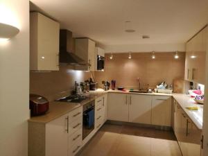 a large kitchen with white cabinets and appliances at Lovet Homestay in London