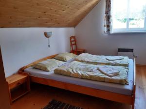 a bed in a bedroom with a wooden ceiling at Chalupa Helena na Poráči in Poráč