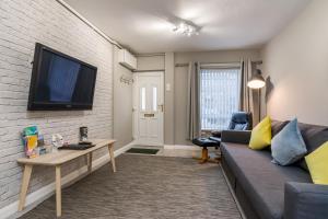 a living room with a couch and a tv on a brick wall at Central Belfast Apartments, Salisbury in Belfast