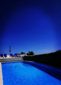a blue swimming pool with chairs and a blue sky at A Quinta da Colina ( Casinha ) in Castanheira de Pêra