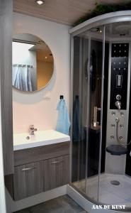 a bathroom with a sink and a shower with a mirror at Zomerhuis "aan de kust" in Egmond aan Zee