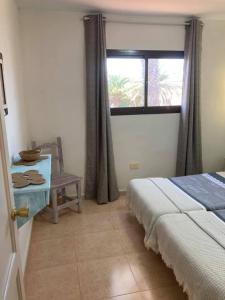a bedroom with a bed and a window and a chair at Casa Camar in Corralejo