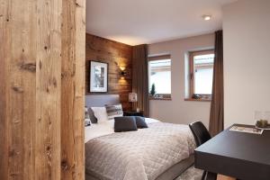 una camera con un letto e una parete in legno di HAHNENKAMM SUITE Ski-in Ski-out direkt an der Hahnenkammbahn a Kitzbühel