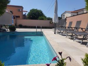 einen Pool mit Stühlen und einem Sonnenschirm in der Unterkunft Villa Slavica in Poreč