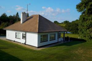 a small white house with a brown roof at Sunrise Cottage on shores off Lough Gowna in Scrabby