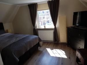 um quarto com uma cama, uma televisão e uma janela em Pension Heidschnucke em Schneverdingen