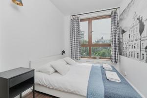 een witte slaapkamer met een bed en een raam bij Apartments Odra Tower Wrocław by Renters in Wrocław