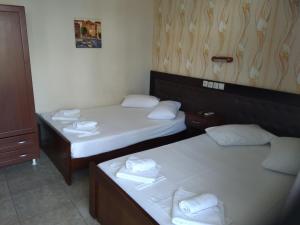 two beds in a hotel room with towels on them at Hotel Villa Pigasos in Paralia Katerinis