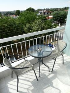 a glass table and two chairs on a balcony at Sea-duction Studios in Nea Iraklia