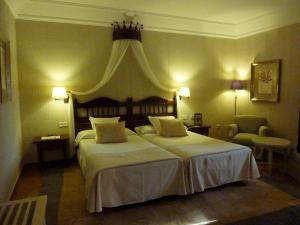 a hotel room with two beds and a chair at Parador de Cuenca in Cuenca