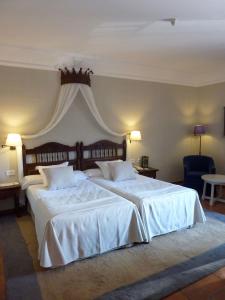 a bedroom with two large beds with white sheets at Parador de Cuenca in Cuenca
