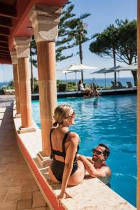 a man and a woman sitting next to a swimming pool at Boutique Hotel Vivenda Miranda in Lagos