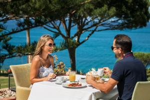 a man and woman sitting at a table eating food at Boutique Hotel Vivenda Miranda in Lagos