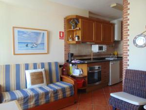 a living room with a kitchen with a couch and a table at Tavira Small cozy flat by the pool and by the sea in Tavira