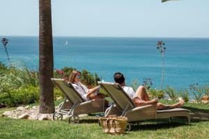 two people sitting in lawn chairs looking at the ocean at Boutique Hotel Vivenda Miranda in Lagos