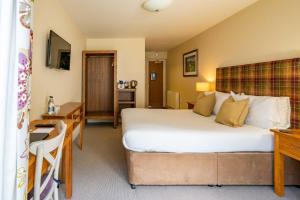 a hotel room with a large bed and a desk at The White Hart, Wroughton in Swindon