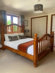 Un dormitorio con una gran cama de madera con sábanas blancas. en Inverasdale, en Oban