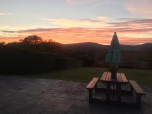 a bench with an umbrella on a patio with a sunset at Bantry Bay Haven in Ballylickey