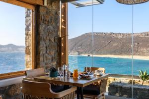 a table in a room with a view of the ocean at Panormos Village Hotel in Mykonos