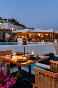 a patio with tables and chairs and a pool at Panormos Village Hotel in Mykonos
